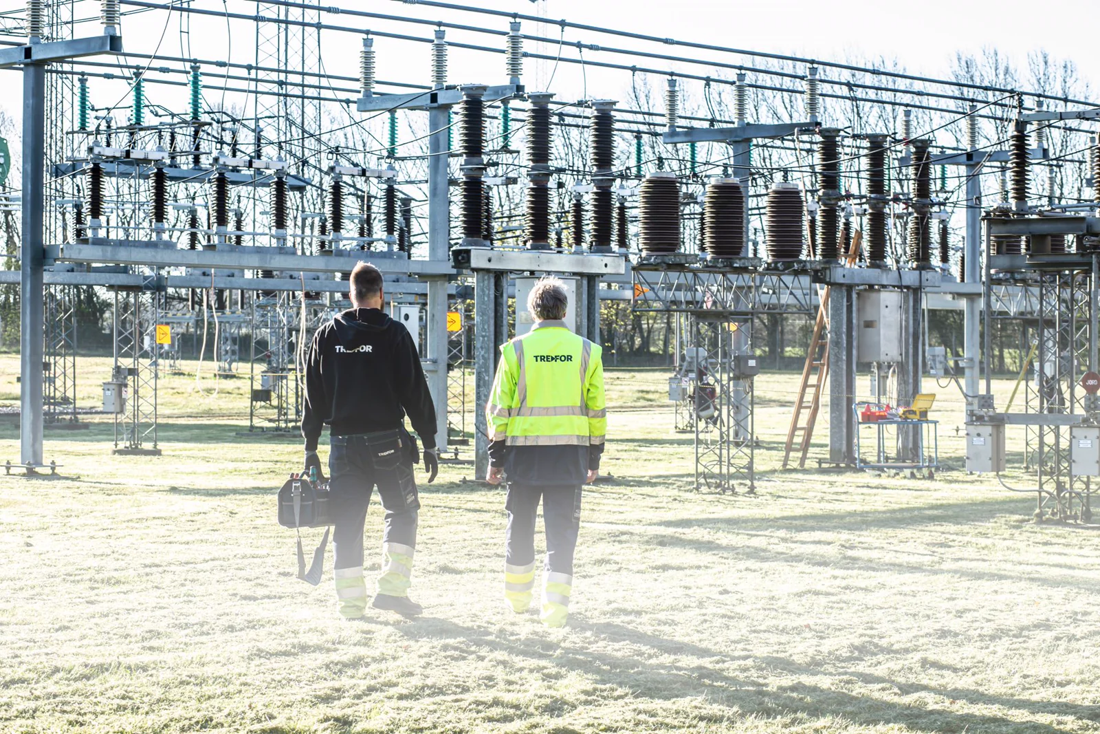 Two workers inspecting an outdoor electrical substation