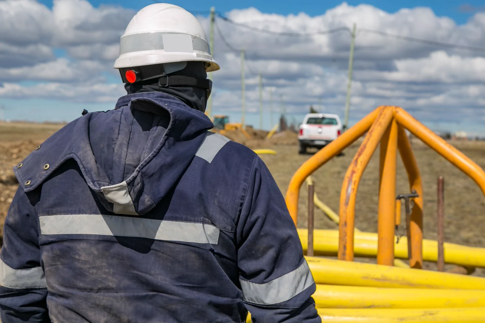 Technician beside stacked pipe at a project site