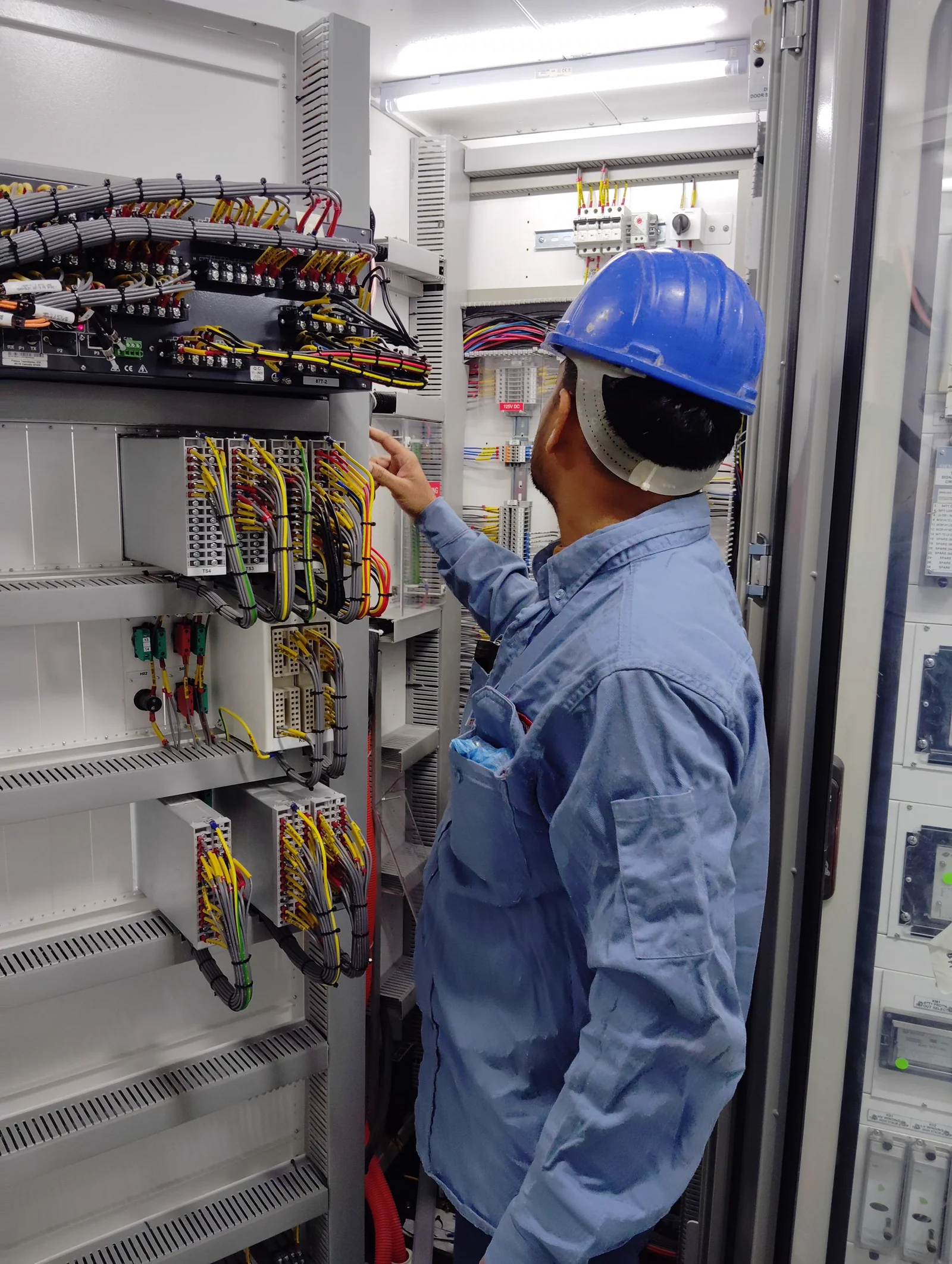 Electrician inspecting an open control panel during a station design review