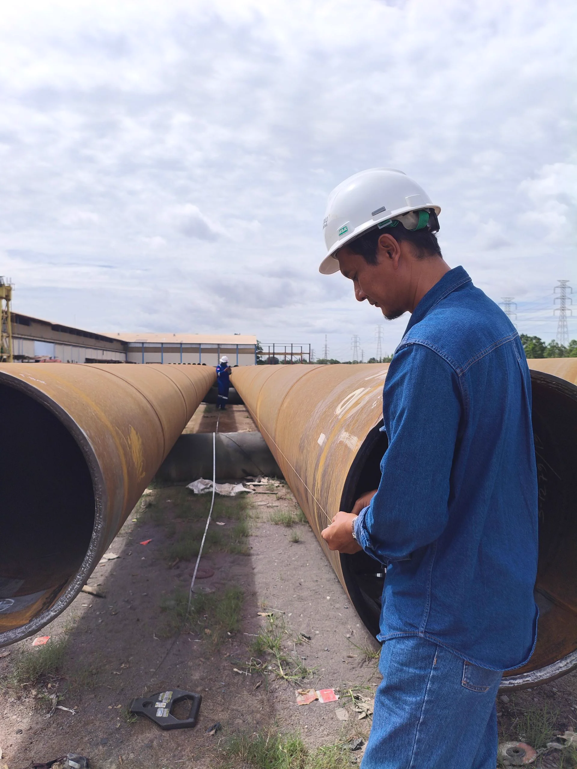 Technician measuring a large-diameter transmission pipe segment, representative of the 140-line ECDA program
